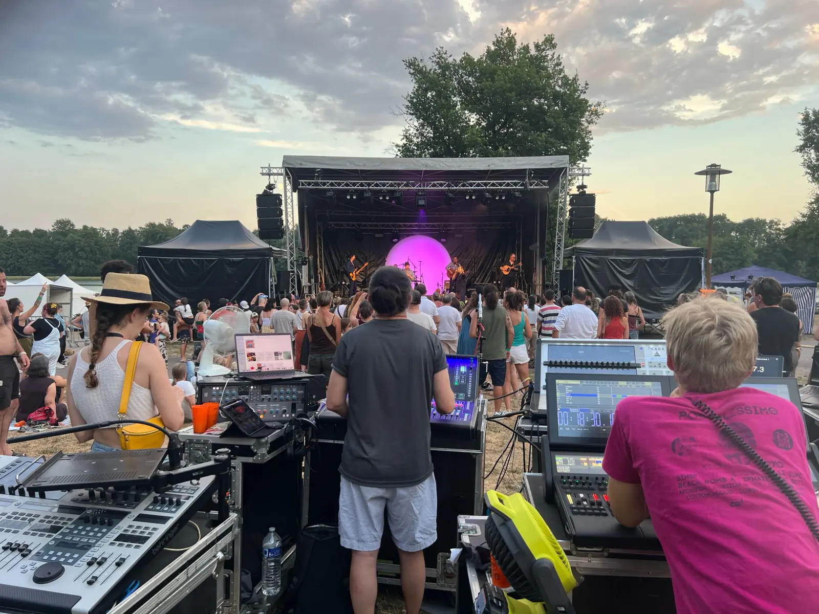 Régie son et lumière d'un festival en plein air en Auvergne, public devant la scène au coucher du soleil